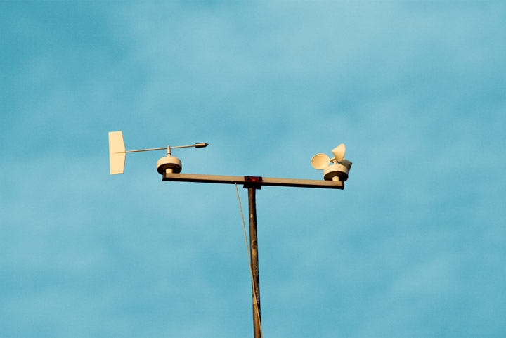 Weather vane and anemonometer against a vivid blue sky