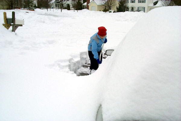 Laura shoveling, from behind the car